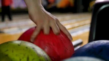 Yakın çekim Genç adam raf gelen bowling topları alıyor. Medya. Kulüp birlikte bowling oynarken rekabetçi neşeli arkadaşlar