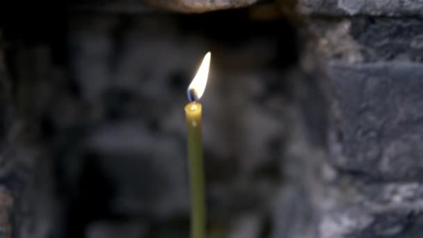 Zblízka hořící svíčku v kamenné stěně. Záběry. Kostelní svíčka — Stock video