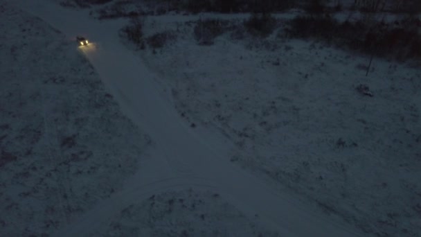 Aerial view of shooting fireworks on the road covered by snow and white car moving outside the city in winter evening. Stock footage. Celebration of the New Year or Christmas — Stock Video