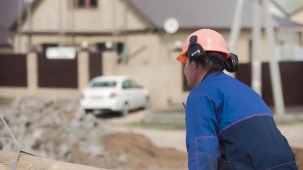 Processo di costruzione di una casa privata. Clip. Costruttore in un casco e uniforme su costruzione della casa privata — Video Stock