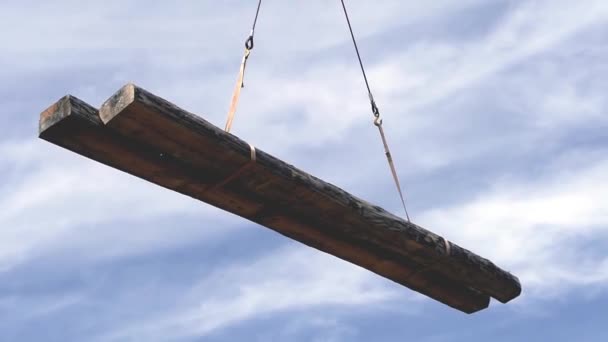 Kran krok håller trä. Klipp. Kran lyfter en balk på en byggarbetsplats. Arbete på byggarbetsplatsen — Stockvideo