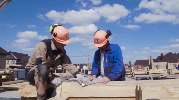 Trabajadores de la construcción en el sitio de construcción uniforme de seguridad. Clip. Dos constructores en un casco en el sitio de construcción — Vídeos de Stock