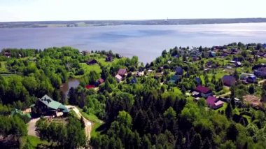 Arka plan mavi göl üzerinde Yazlık şehir. Klip. Gölün yanında bir orman alanında bir köy üst görünümü