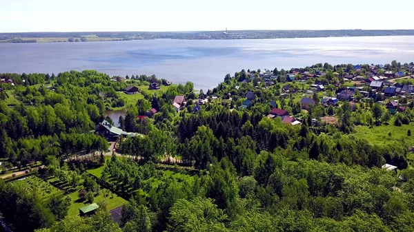 Hüttenstadt auf blauem See im Hintergrund. Clip. Blick von oben auf ein Dorf in einem Waldgebiet am See — Stockfoto