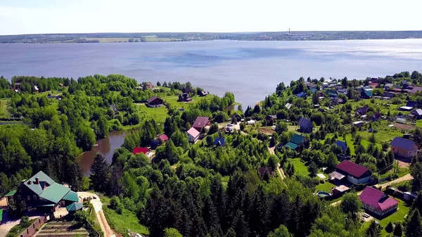 Hüttenstadt auf blauem See im Hintergrund. Clip. Blick von oben auf ein Dorf in einem Waldgebiet am See — Stockfoto