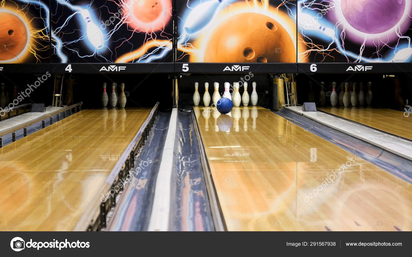 Blue bowling ball and white skittles standing on a wooden bowling alley