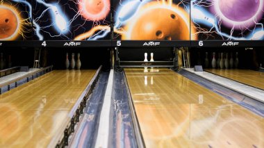 Mavi bowling topu ve beyaz skittles ahşap bir bowling salonu, aktif spor oyunları kavramı üzerinde duran. Medya. Mavi top şeritte yuvarlanan ve beyaz pimleri deviren.