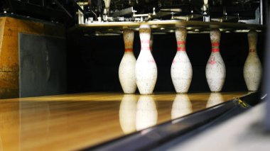 Bowling salonu nun sonunda duran bowling pimlerinin ve bir spor kulübünde ahşap yüzeyde yuvarlanan bowling topunun manzarası. Bir bowling komik spor hafta sonları