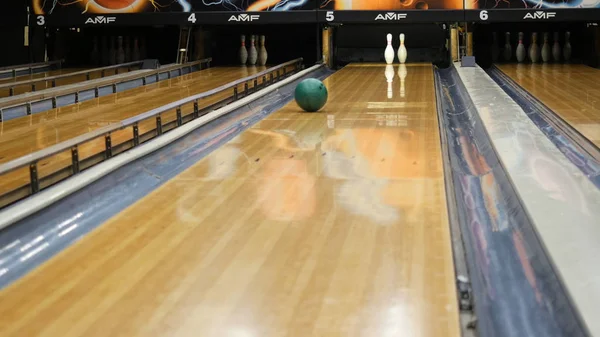 Vista ravvicinata di persona che lancia la palla da bowling sulla pista da bowling e cerca di ottenere spilli in un club sportivo. I media. Weekend sportivi divertenti in un bowling — Foto Stock