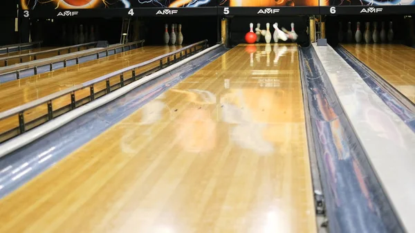 Vista ravvicinata di persona che lancia la palla da bowling sulla pista da bowling e cerca di ottenere spilli in un club sportivo. I media. Weekend sportivi divertenti in un bowling — Foto Stock