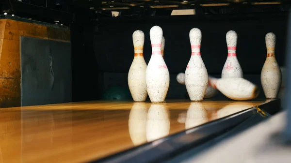 Vista di birilli da bowling in piedi alla fine della pista da bowling e palla da bowling rotolando sulla superficie di legno in un club sportivo. Weekend sportivi divertenti in un bowling — Foto Stock