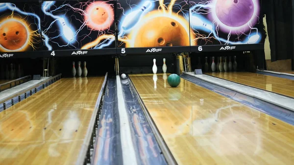 Persone che giocano a bowling - palla colorata che colpisce i birilli da bowling sulla pista da bowling in un club sportivo. I media. Il concetto di sistema di ritorno palle da bowling macchina — Foto Stock