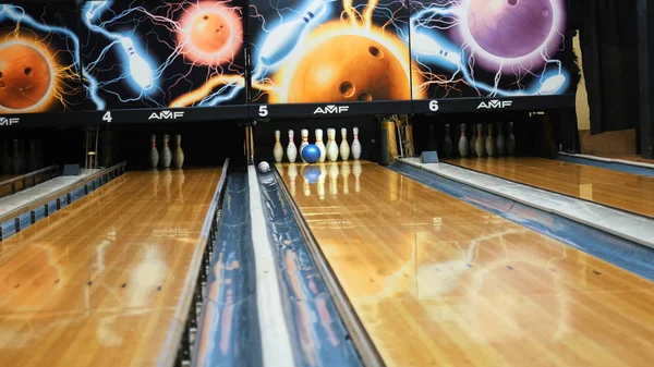 Lidé hrají kuželky s barevným míčkem a dopadávají na bowlingové kolíky ve sportovním klubu. Media. Bowlingové míče vracejí koncept strojového systému — Stock fotografie