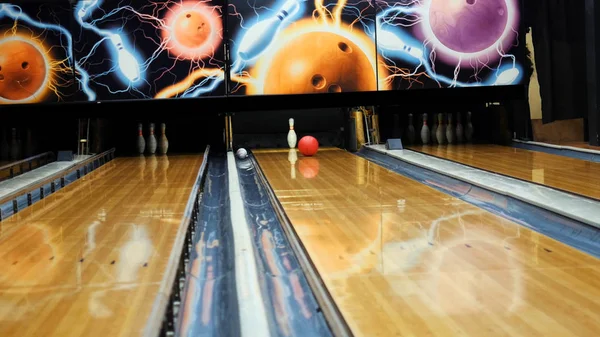 Persone che giocano a bowling - palla colorata che colpisce i birilli da bowling sulla pista da bowling in un club sportivo. I media. Il concetto di sistema di ritorno palle da bowling macchina — Foto Stock