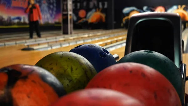 Close-up view of bowling player hand taking colorful ball from bowl lift. Media. People playing bowling - the bowling balls return machine system concept