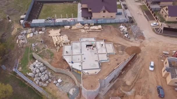 Luftaufnahme der neuen modernen Hütte in der Nähe der Baustelle, Baumaterialien und Arbeiter, die Beton für das Fundament gießen. Clip. Prozess des Neubaus. — Stockvideo