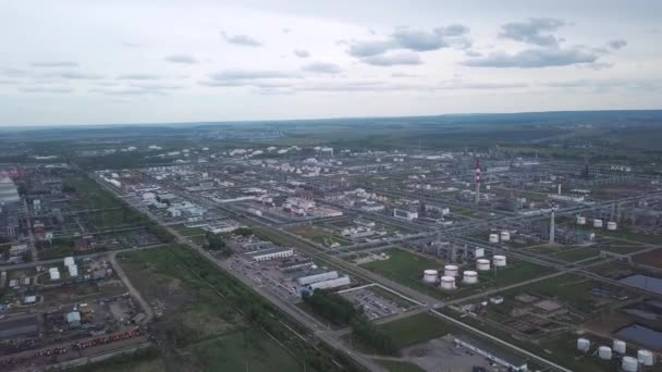 Bulutlu gökyüzüne karşı arka planda alanları ve ağaçları ile şehir dışında bulunan büyük sanayi bölgesinin yukarıdan görünümü. Klip. Fabrika tankları ve tank çiftliği inanılmaz görünümü. — Stok video