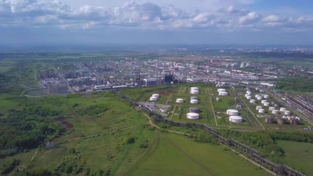 Vue aérienne du champ avec des arbres près de la zone industrielle située à l'extérieur de la ville. Clip. Vue imprenable sur les usines réservoirs et le parc de réservoirs pour le stockage de pétrole et d'essence en vrac 