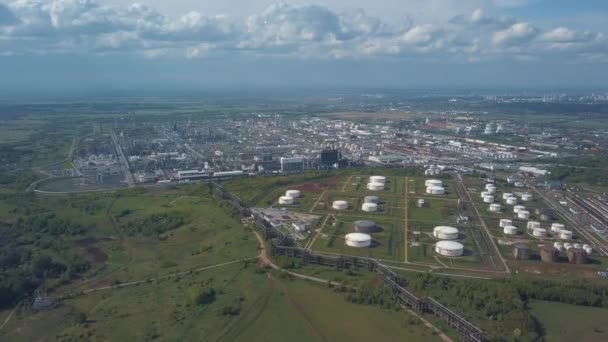 Vue aérienne du champ avec des arbres près de la zone industrielle située à l'extérieur de la ville. Clip. Vue imprenable sur les usines réservoirs et le parc de réservoirs pour le stockage de pétrole et d'essence en vrac 