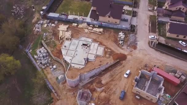 Vista aérea de la nueva casa moderna cerca del sitio de construcción, materiales de construcción y trabajadores vertiendo hormigón para la fundación. Clip. Proceso de construcción de edificios nuevos . — Vídeo de stock