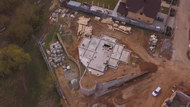Widok z lotu ptaka na placu budowy w toku w pobliżu nowego nowoczesnego domku, materiałów budowlanych i pracowników odlewania betonu na fundamencie. Klip. Proces budowy nowych budynków. — Wideo stockowe