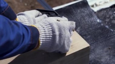 Ahşap tahtaya bir şeyler yazan koruyucu eldivenli bir marangozun ellerini kapatın. Şarjör. Doğrama işleri, ölçüm ve işaretleme ahşap, ahşap işçiliği ve mobilya yapma kavramı.