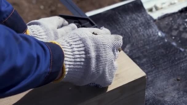 Close up for hands of a carpenter in protective gloves writing something on a wooden board. Clip. Joinery works, measuring and marking the wood, woodwork and furniture making concept. — Stock Video