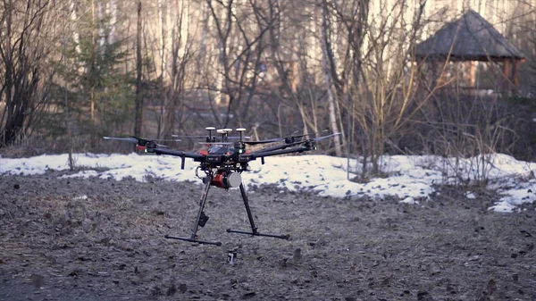 Gros plan pour drone noir debout au sol avant le vol, vidéo aérienne et photo concept de prise de vue. Clip. Quadcopter commence à faire pivoter ses lames et à décoller . — Photo