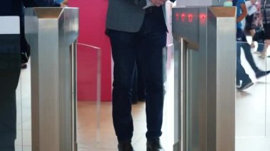 Gri takım ceketli adam ve barkod tarayıcı ile elektronik turnike geçen mavi kot pantolon. Medya. İş merkezi için erişim kontrolü, yakın çekim