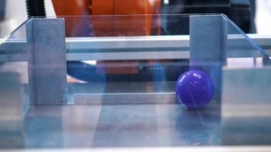 Büyük turuncu robotik el bir bölümden diğerine küçük plastik çok renkli topları taşınması. Medya. Robotik Forumu sergisinde farklı çalışan robotlar koleksiyonu sunuldu