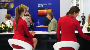 Yekaterinburg, Rusya - Temmuz, 2019: Rusya'daki bilimsel serginin kayıt masasında oturan kırmızı elbiseli iki genç kadın. Medya. Elektronik cihazlar ve endüstriyel mekanizmalar