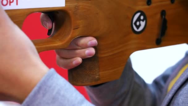 Close-up of man holding a weapon and shooting in virtual reality on the exhibition. Media. Electronic devices and mechanisms are presented at the scientific exhibition. — Stock Video