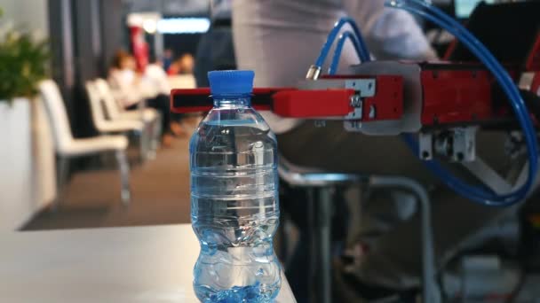 Close-up view of robotic hand holding and relocating a bottle with water on the exhibition. Media. Different working robots collection presented on the robotics forum exhibition — Stock Video