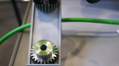 Otomatik robot cihazın yanında masanın üzerinde yatan küçük metal dişlilerin yakın çekim. Medya. Elektronik cihazlar ve mekanizmalar bilimsel sergide sunuluyor.