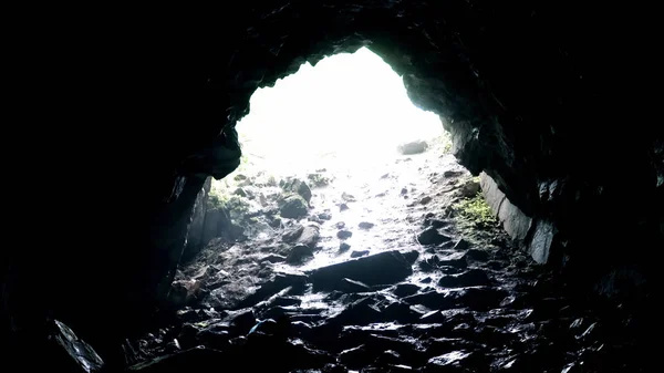 Saia da caverna rochosa escura. Imagens de stock. Luz brilhante na saída de caverna rochosa coberta da escuridão na umidade. Humidade e humidade em cavernas em tempo nublado — Fotografia de Stock