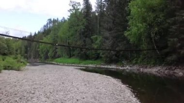Orman Nehri üzerindeki ahşap köprü seviyesinde görüntüleyebilirsiniz. Stok görüntüleri. Orman Nehri'ni geçen turistler için asma ahşap köprünün üst görünümü