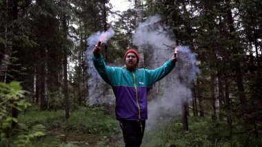 Ormanda adam ve renkli sis bombaları. Stok görüntüleri. Genç adam güzel fotoğraf için ormanda duman renkli dama yaktı