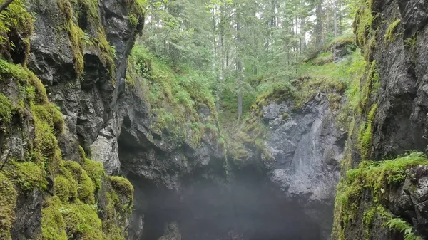 Top view of gorge between rocks in forest. Stock footage. Two cliffs covered with moss hang over small gorge with fog on background of forest. Gorge suggestive fear your mystical haze — Stock Photo, Image
