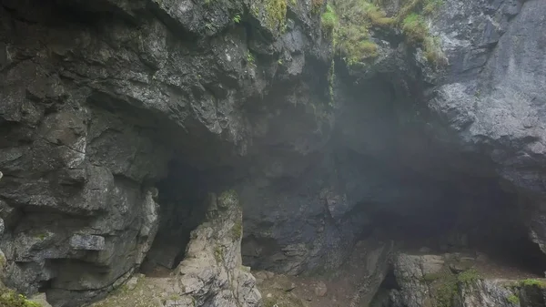 Top view of gorge between rocks in forest. Stock footage. Two cliffs covered with moss hang over small gorge with fog on background of forest. Gorge suggestive fear your mystical haze