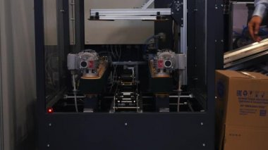 Büyük bir karton kutu alarak bir cam kabin robot makinenin yakın çekim görünümü. Medya. Robotik Forumu sergisinde farklı çalışan robotlar koleksiyonu sunuldu