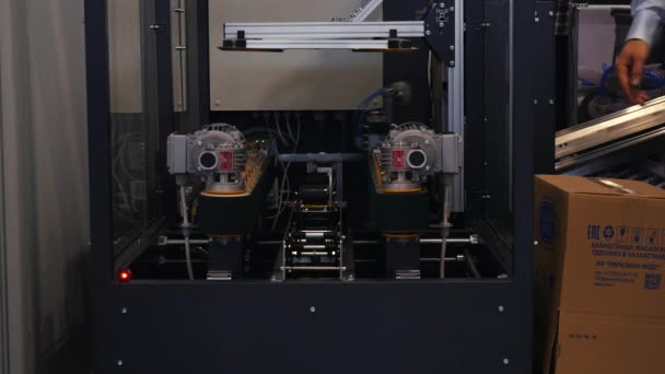 Vista de cerca de la máquina robot en una cabina de vidrio que toma una caja de cartón grande. Medios. Diferentes colecciones de robots de trabajo presentadas en la exposición foro de robótica — Vídeo de stock