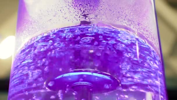 Vařící voda ve velkém skleněném chladničce s neónovou podsvětelnou a kovovou trubkou. Media. Podrobný pohled na nadmořskou vodu v chladničce s bublinami svítí barevným světlem — Stock video
