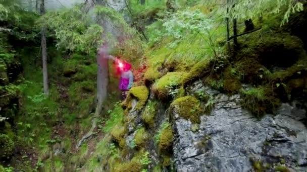 Hombre con señal de fuego en la naturaleza. Imágenes de archivo. Vista superior de viajero perdido en el bosque y en la desesperación encendió la bomba de humo roja para el rescate. Equipo de señalización de rescate. Bengala de mano — Vídeos de Stock