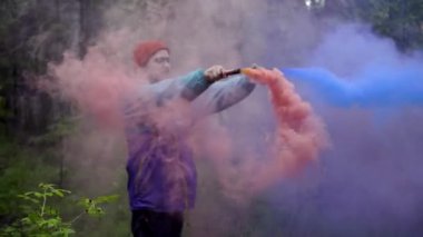 Hipster'da renkli sis bombaları var. Stok görüntüleri. Genç adam güzel fotoğraf için yeşil ormanda renkli sis bombaları dispels