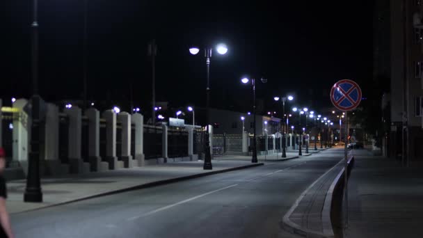 Carretera vacía iluminada por faroles en la noche. Imágenes de archivo. Noche de verano en la ciudad iluminada por luces blancas se vacía en las carreteras en el momento posterior — Vídeo de stock