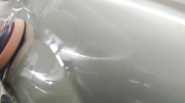 İşçinin yakın çekim icarı parlatır. Stok görüntüleri. İşçi atölyede parlatma için otomatik makine nin araç gövdesini parlatır. Yumuşak yüzey parlatma otomobil gövdesine parlaklık katar