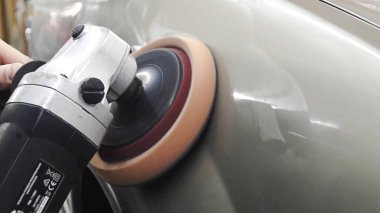 İşçinin yakın çekim icarı parlatır. Stok görüntüleri. İşçi atölyede parlatma için otomatik makine nin araç gövdesini parlatır. Yumuşak yüzey parlatma otomobil gövdesine parlaklık katar