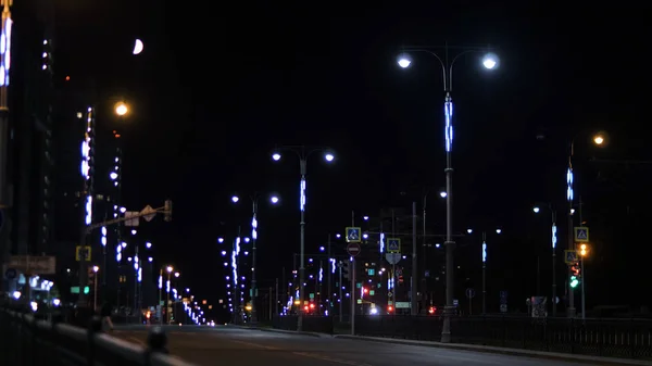 Fények a város éjjel az úttesten. Stock Footage. Éjszakai város gyönyörű neonfények a közúti. Nyári éjszaka a városban, az üres úton a lámpások homályos fényében világít — Stock Fotó