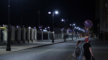 Geceleri fenerlerle aydınlatılmış boş bir yol. Stok görüntüleri. Beyaz ışıklarla aydınlatılan şehirde yaz gecesi daha sonra yollarda boşalıyor