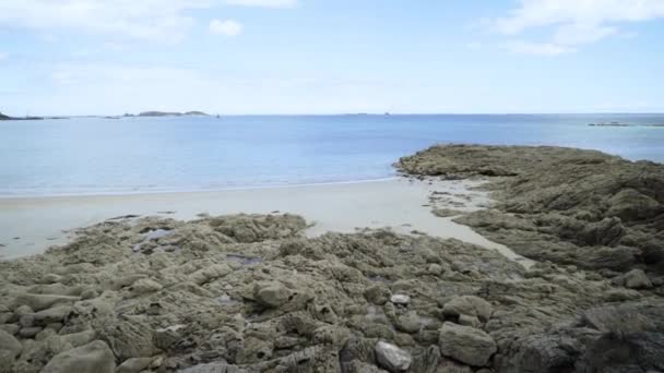 青い海の背景に石と砂とビーチ。アクション。空と海の地平線を背景に砂と石と美しい野生のビーチのパノラマ — ストック動画